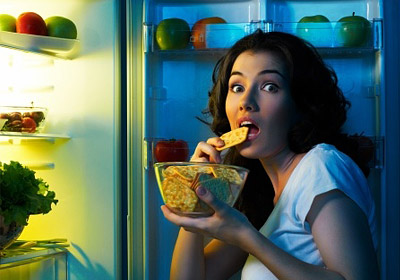 a lady eating at midnight in front of the fridge
